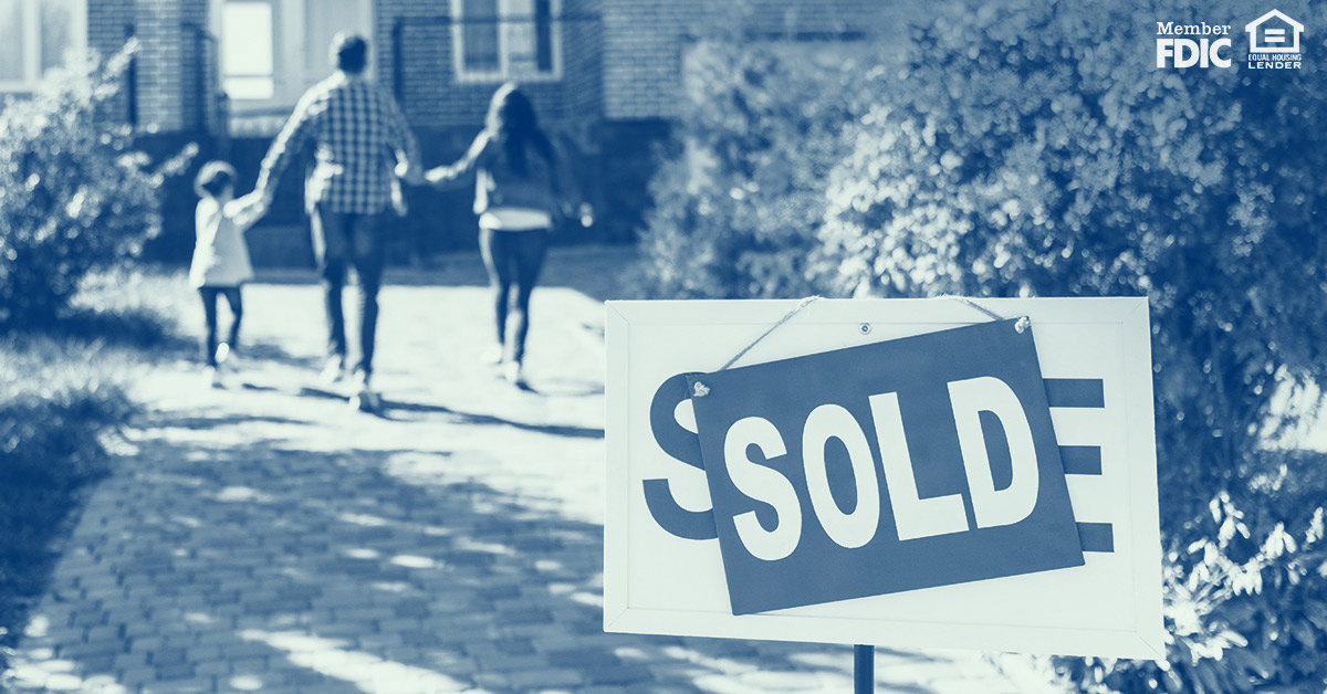 Blue-scale photo shows a "SOLD" sign in the foreground and a family walking down the driveway of their new home in the background.
